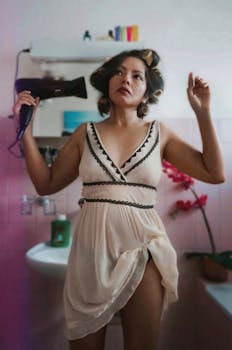 A woman styling her hair with curlers and a hairdryer in a vintage-themed bathroom.