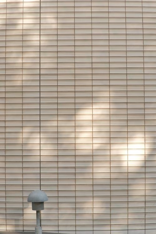 Free Textured white wall featuring soft shadows and a minimalist lamp post Stock Photo