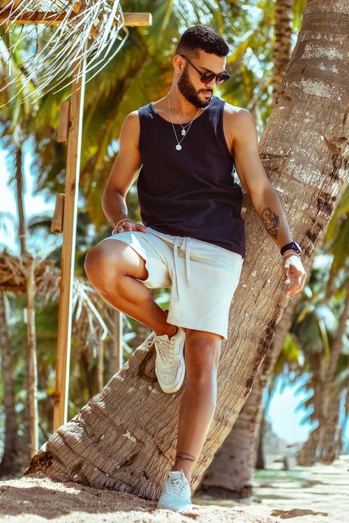 Handsome Man in White Short Posing in Front of Palm Tree · Free Stock Photo