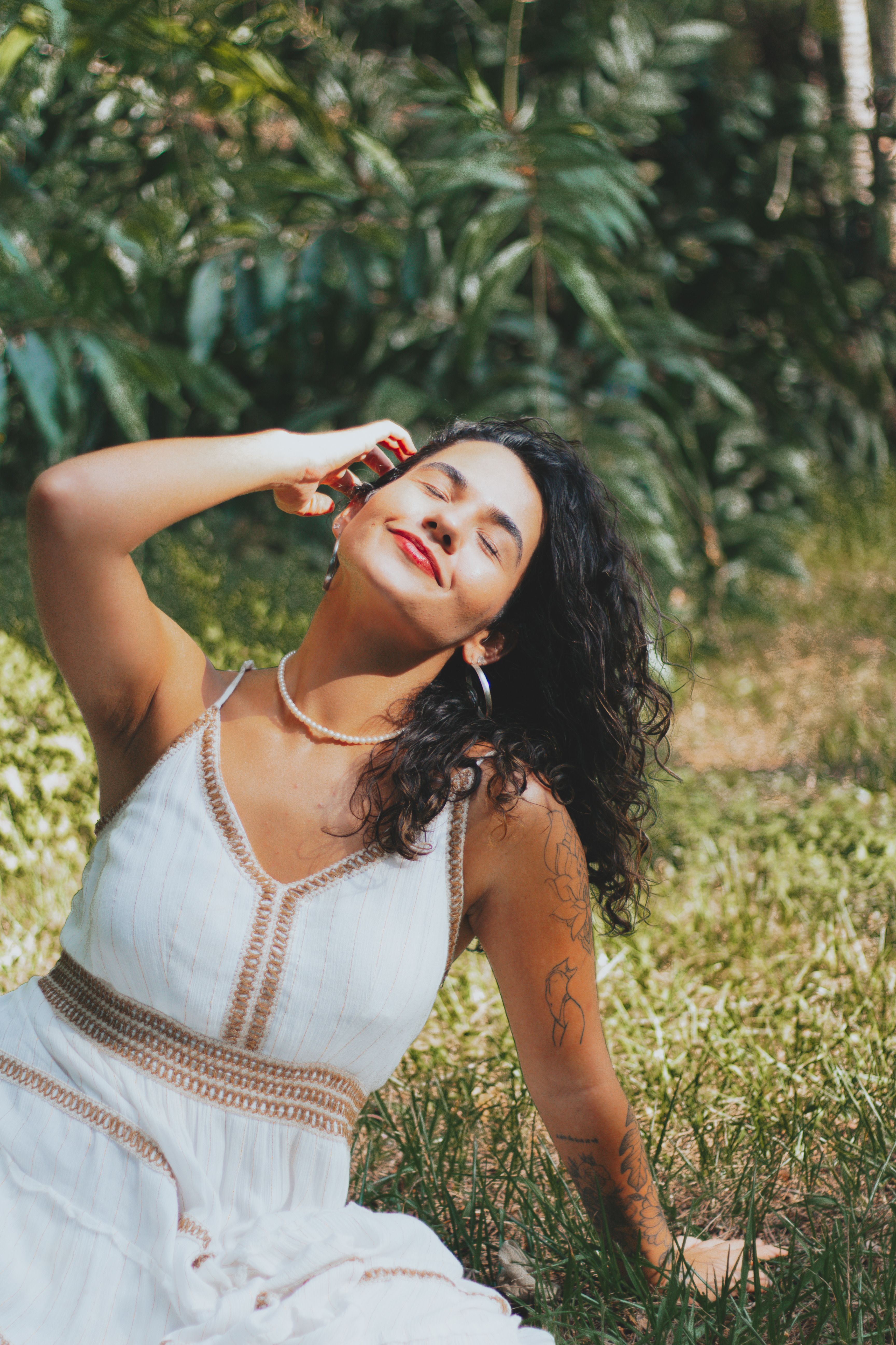 Young Woman in a White Dress Sitting on the Ground and Facing the Sun ...