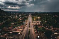 Aerial view of a main road in Arusha, Tanzania, with overcast skies and surrounding greenery.