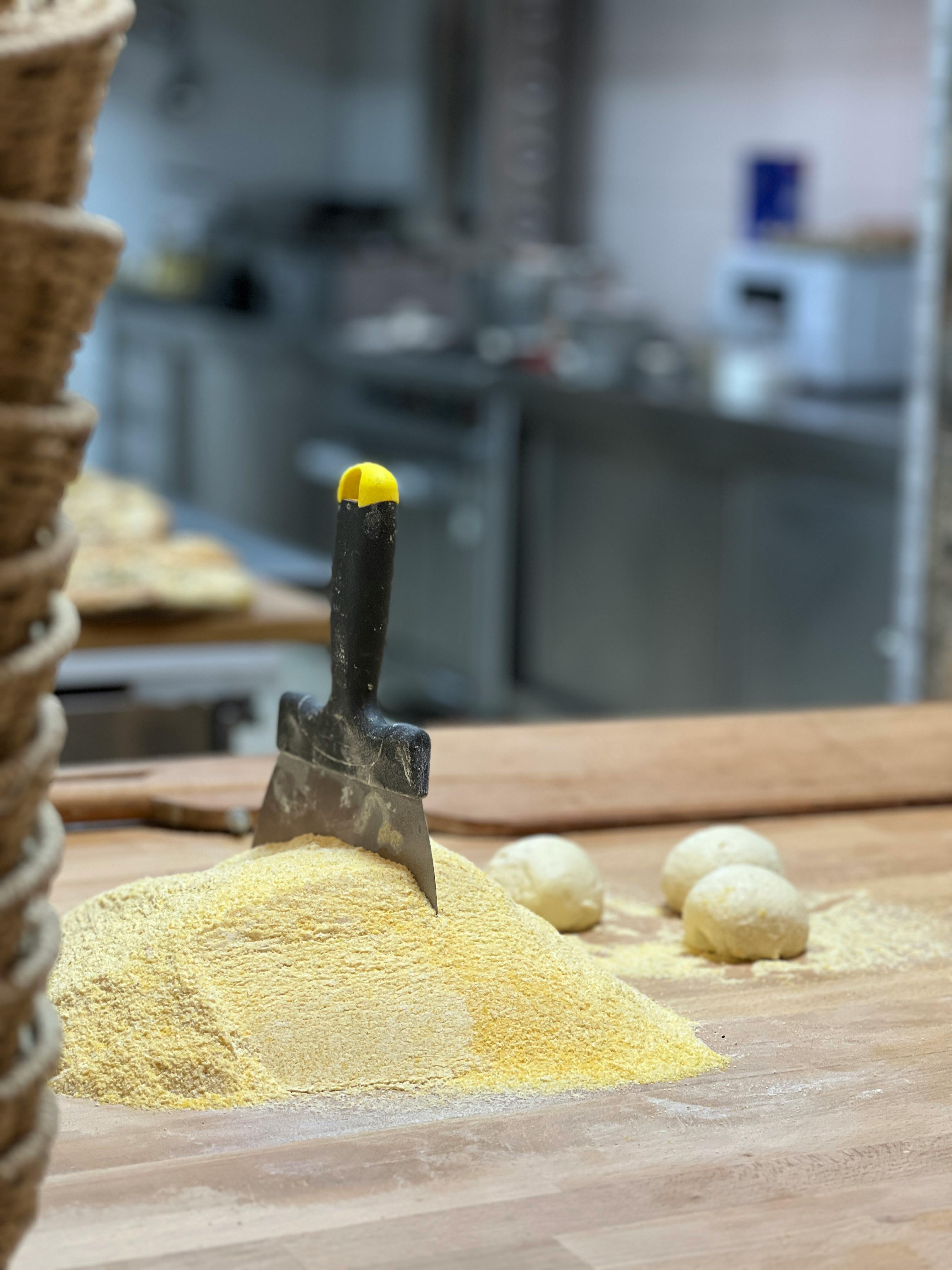 A Spatula in the Flour and Raw Dough Balls on the Counter in a Bakery