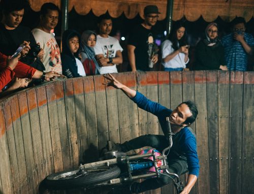 Free A biker performs a thrilling stunt on a wall of death surrounded by an eager audience. Stock Photo