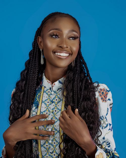 Free Portrait of a smiling woman with long braided hair, set against a blue background. Stock Photo