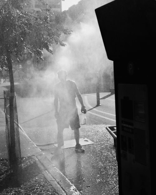 Free Moody urban black and white scene featuring a person standing amid steam on a city pavement. Stock Photo