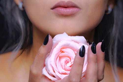 Женщина, держащая розовый цветок розы