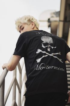 Fashion-forward man with dyed hair ascending stairs in a skull-themed T-shirt.