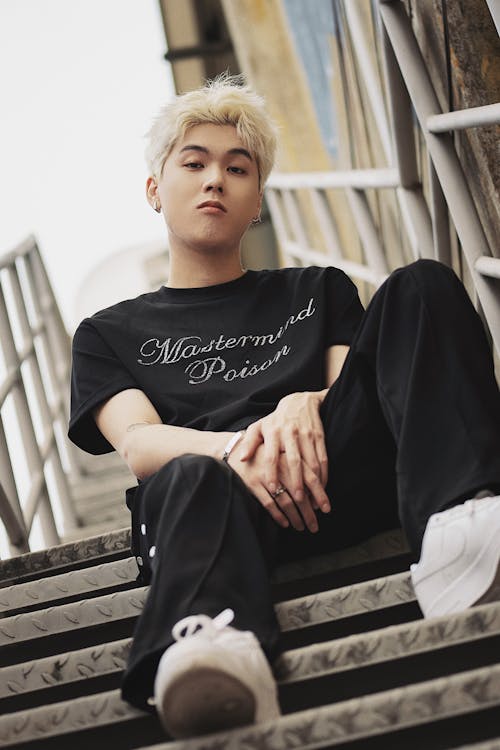 Man with Dyed Hair Sitting on Stairs and Posing