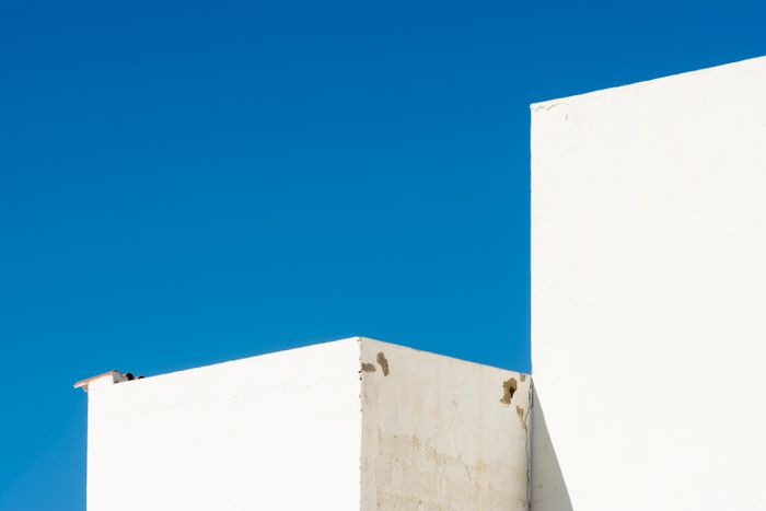 Whitewashed rooftop walls against a deep blue sky, photo by Jan van der Wolf on Pexels