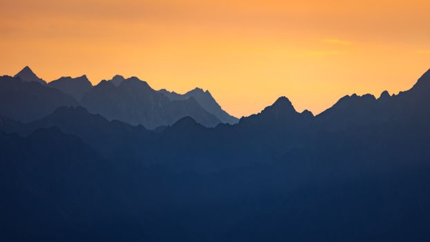A breathtaking view of silhouetted mountains against a vibrant sunset sky, showcasing nature's tranquility.