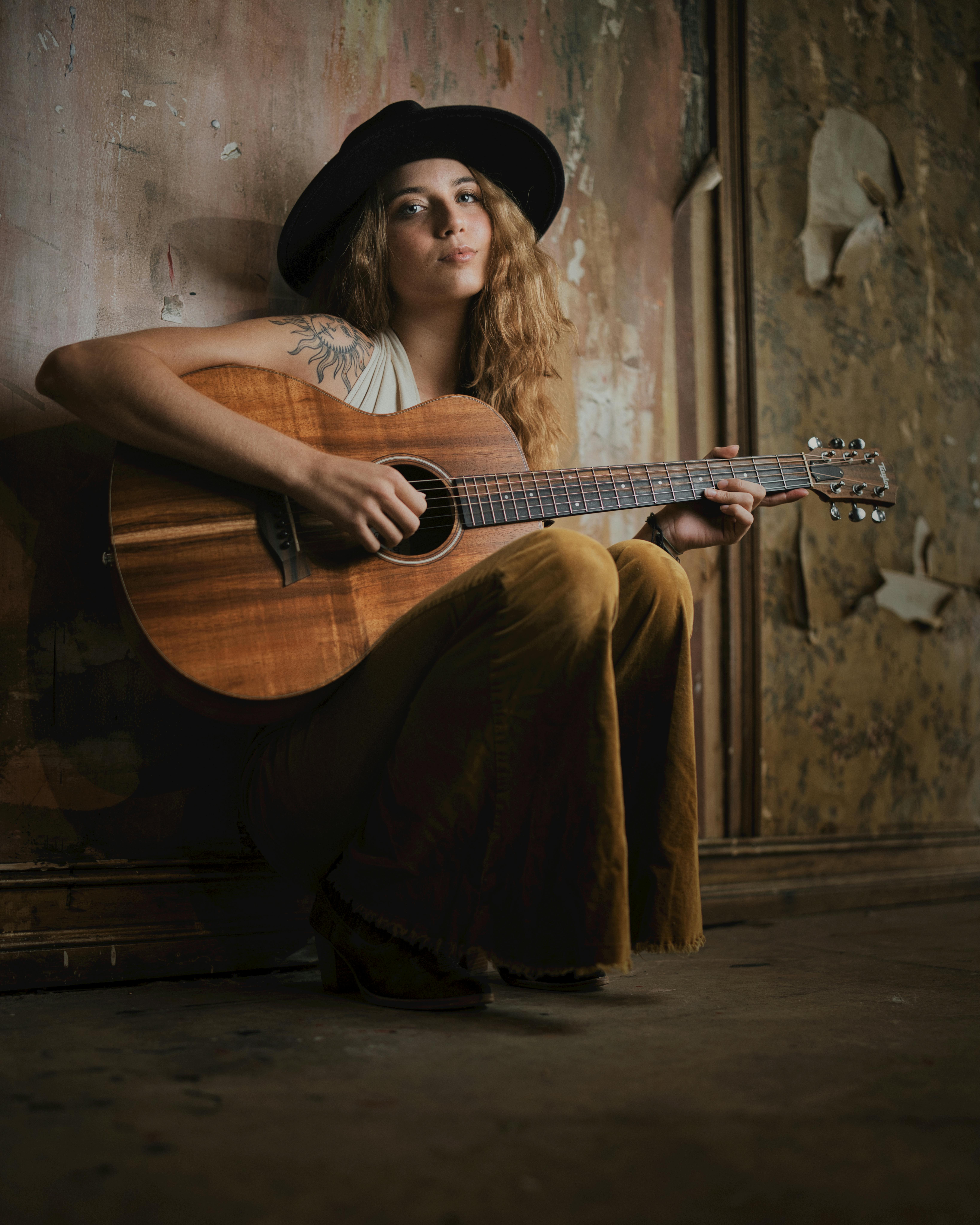 young woman in cowboy hat playing guitar
