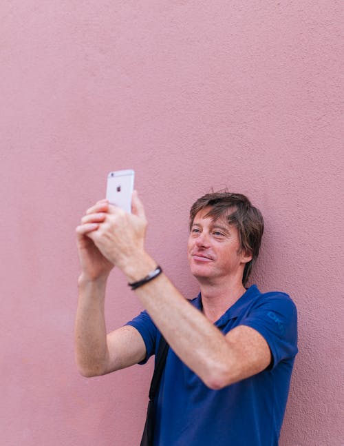 Free Man Taking Selfie While Leaning on Wall Stock Photo
