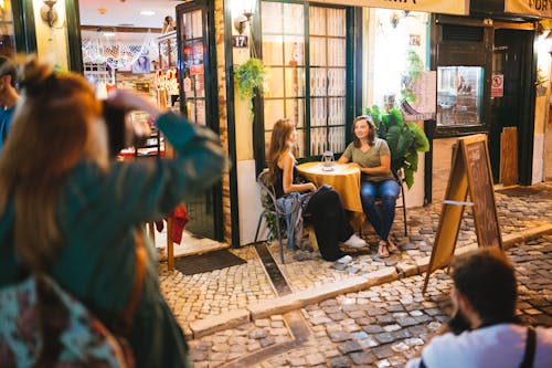 免费 两个男人和女人拍照的两个女人坐在和谈与菜单板路旁的圆桌旁 素材图片