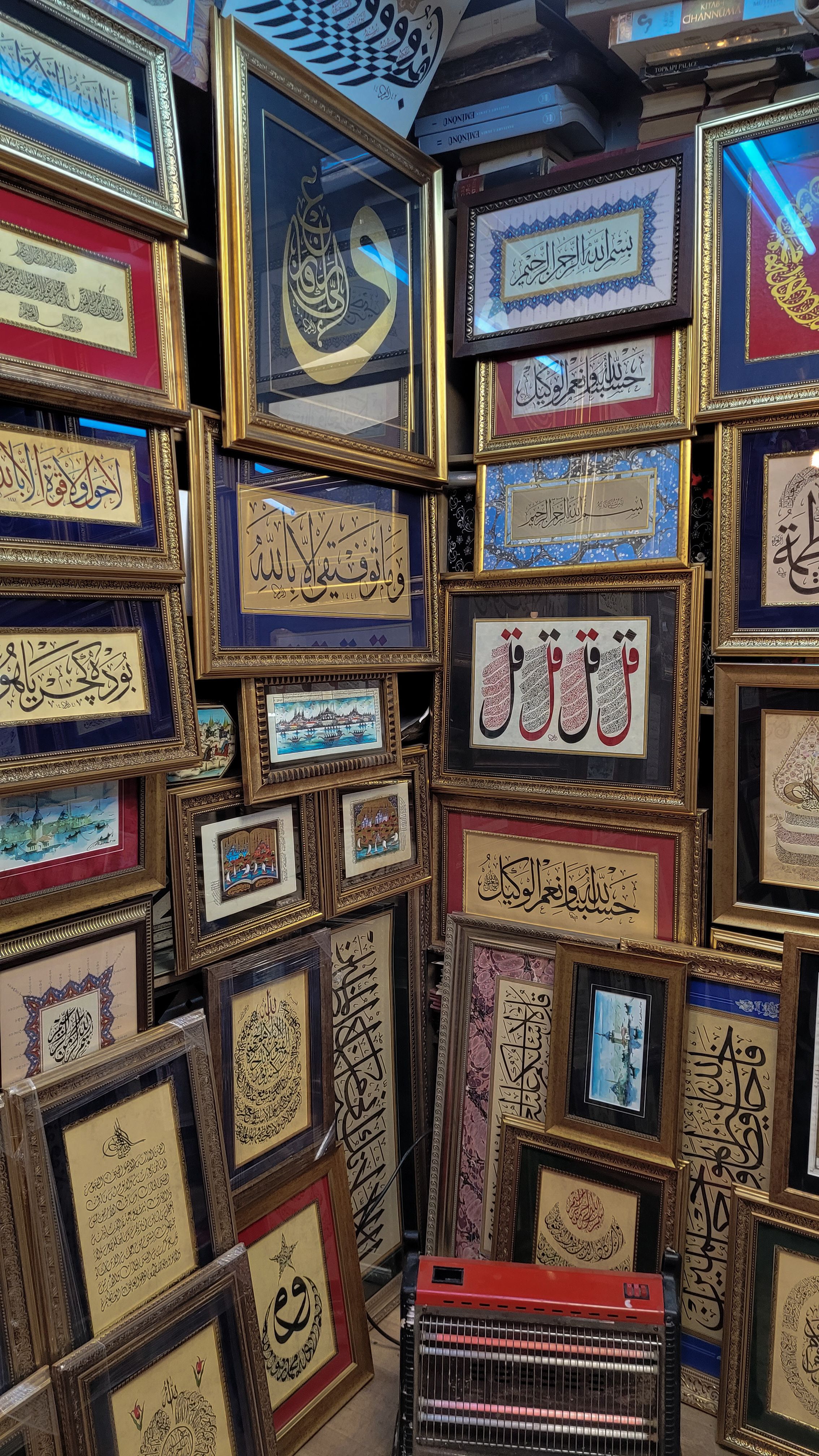 A vibrant display of various gold-framed Arabic calligraphy artworks with intricate ornamentation.