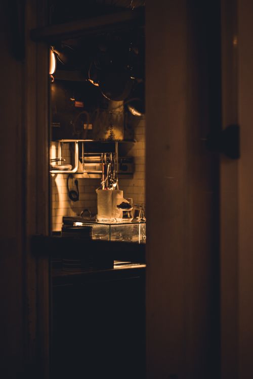 Free Cozy kitchen interior with warm lighting visible through a doorway. Stock Photo