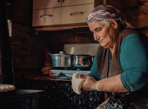 Free Senior woman baking traditional bread in a rustic kitchen, Artvin, Türkiye. Stock Photo