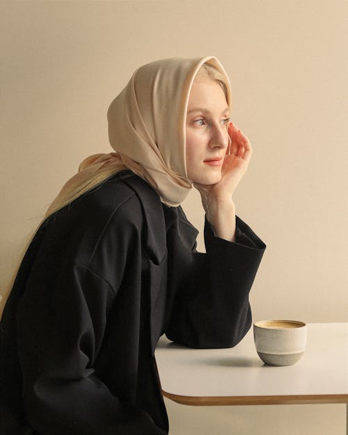 Woman in Hijab by Table with Cup