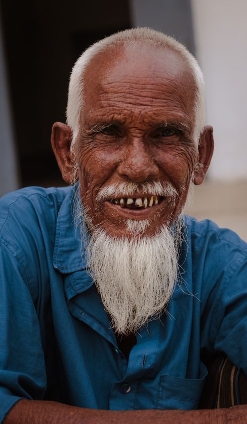 Free A close-up portrait of a smiling elderly man with a long white beard and blue shirt. Stock Photo