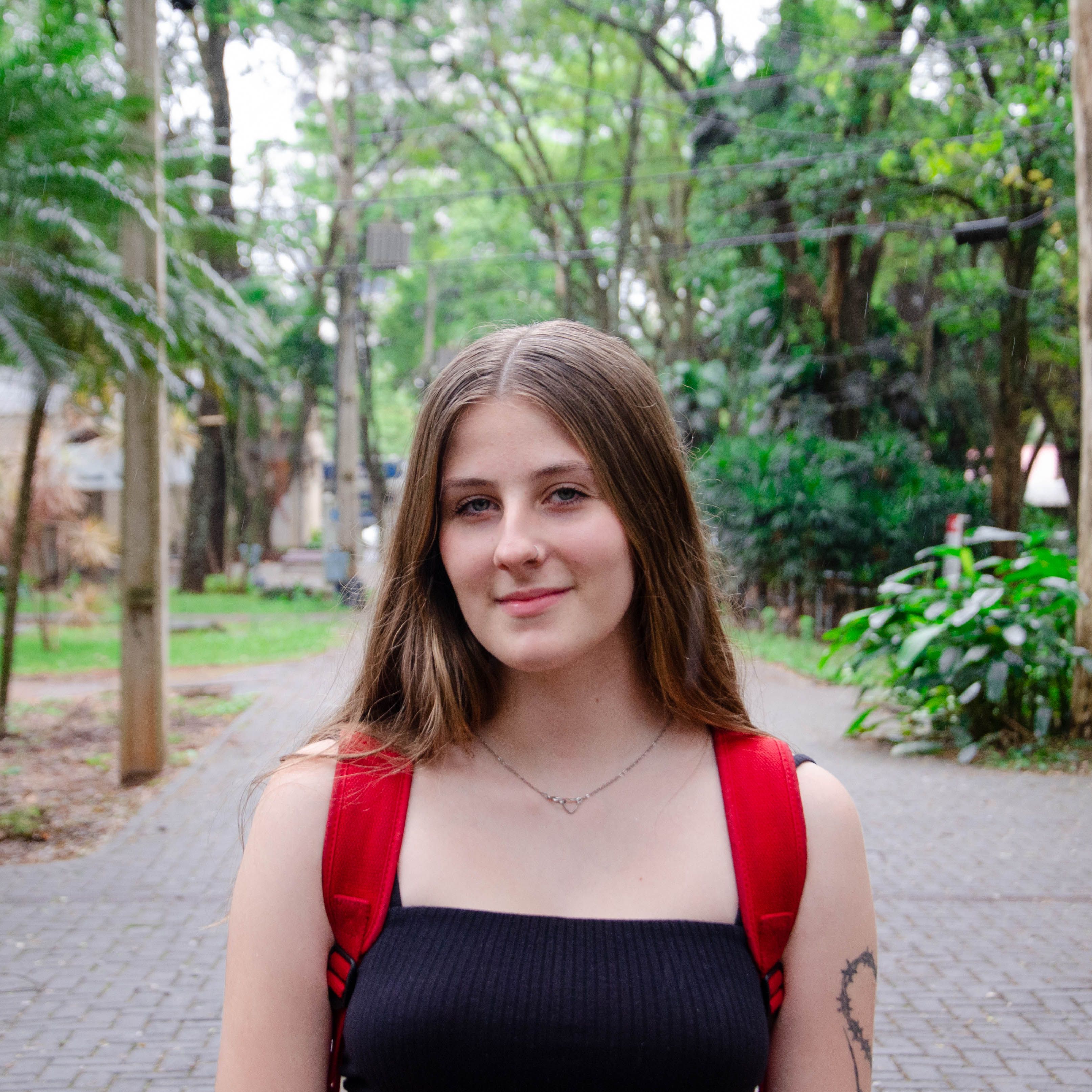Young woman smiling in a green park with a red backpack