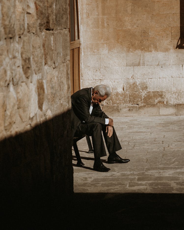 A Man In Suit Sitting On A Bench