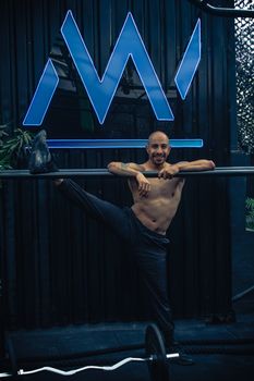 Athletic man stretching on gym equipment indoors, emphasizing fitness and flexibility.
