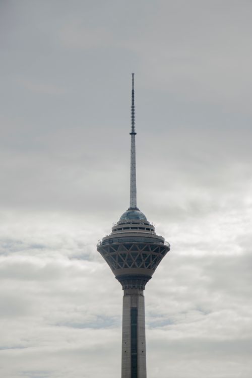 Free Milad Tower rises against a cloudy sky in Tehran, showcasing modern architecture. Stock Photo
