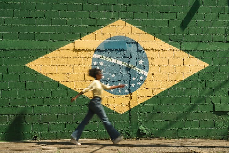 Girl Walking On Street With Brazilian Flag On Wall