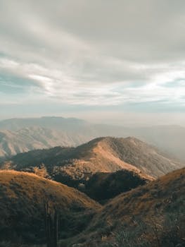 Scenic view of a mountain range under a dramatic sky with soft sunlight. Perfect for nature themes.