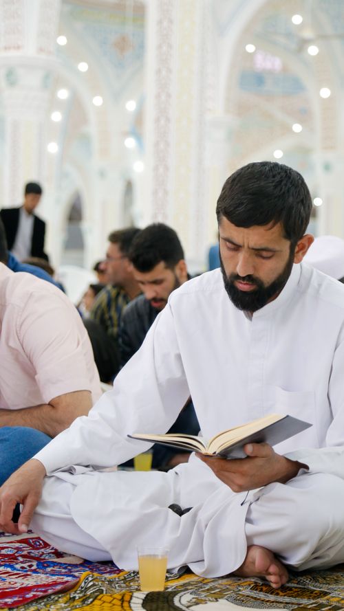 Free A man is reading a book in a mosque setting in Khaf, Iran, capturing a serene moment. Stock Photo