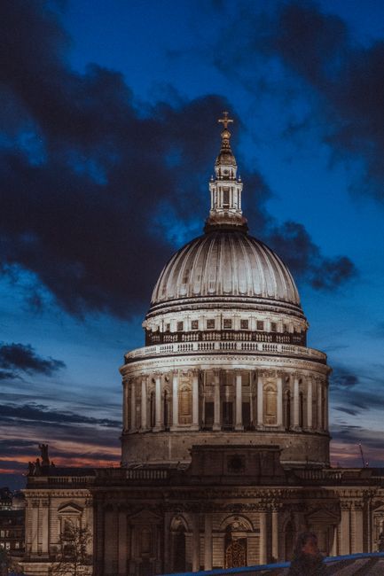 Iconic St Paul's Cathedral dome illuminated against a dramatic evening sky in London.