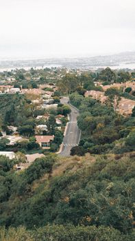 Aerial view of a winding road through lush greenery and suburban homes in San Diego, California.