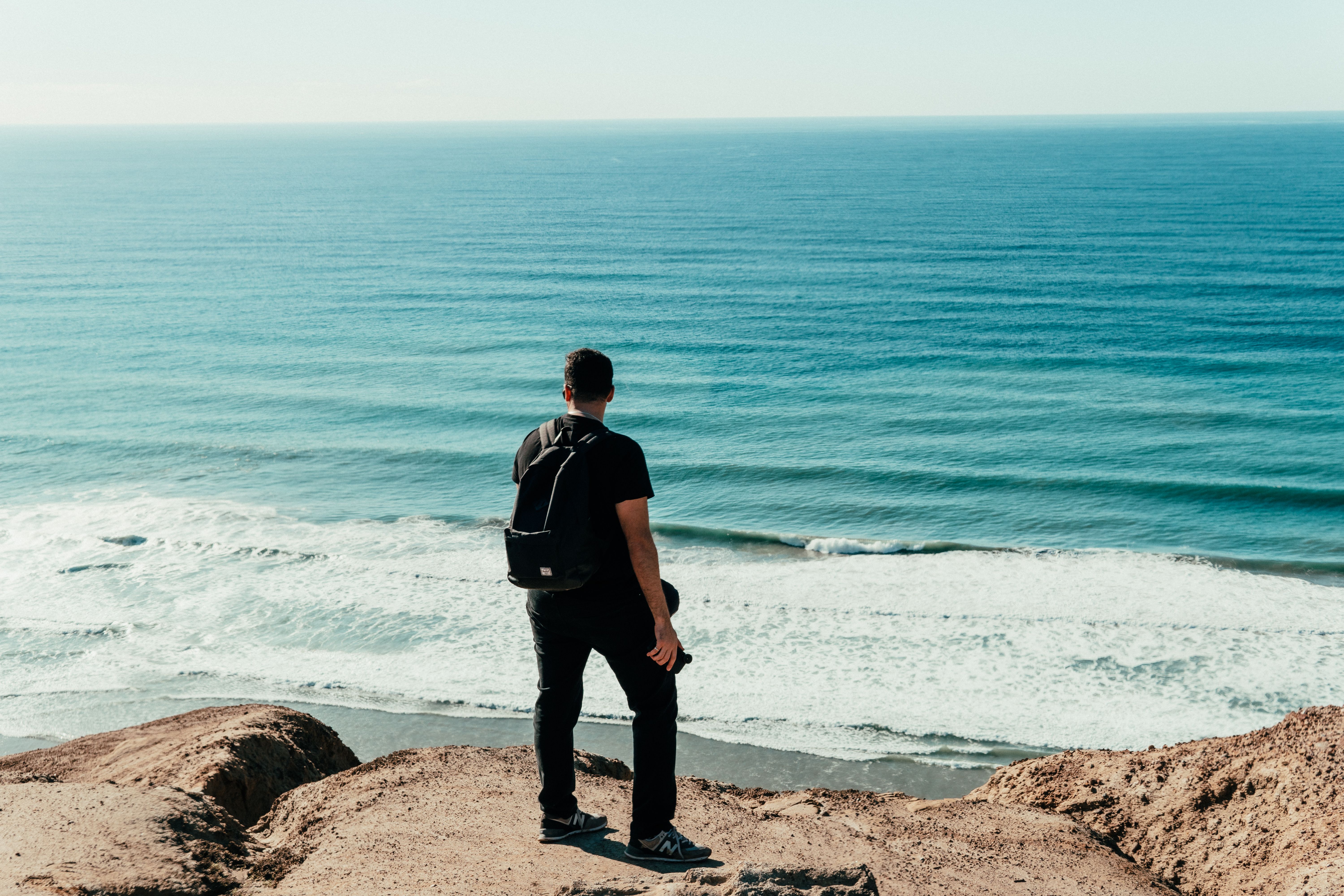 a man standing on top of a sandy beach next to the ocean · Free Stock Photo