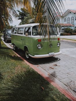 一辆经典的绿色货车停在阳光明媚、棕榈树成荫的街道上，营造出复古的旅行氛围