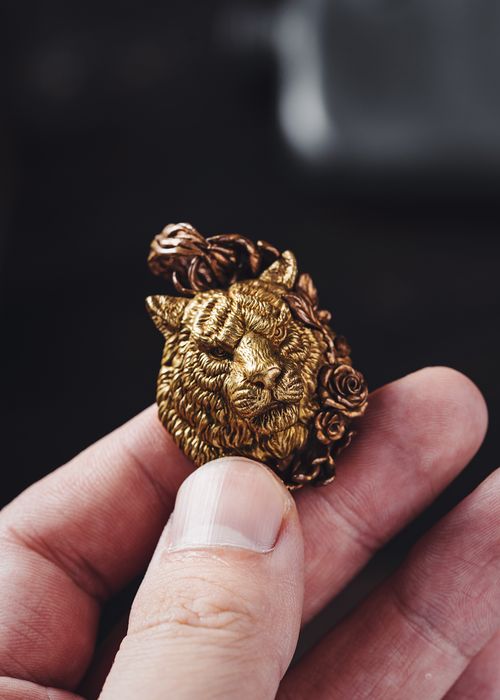 Free Intricate gold lion pendant held in a hand, showcasing fine jewelry craftsmanship. Stock Photo