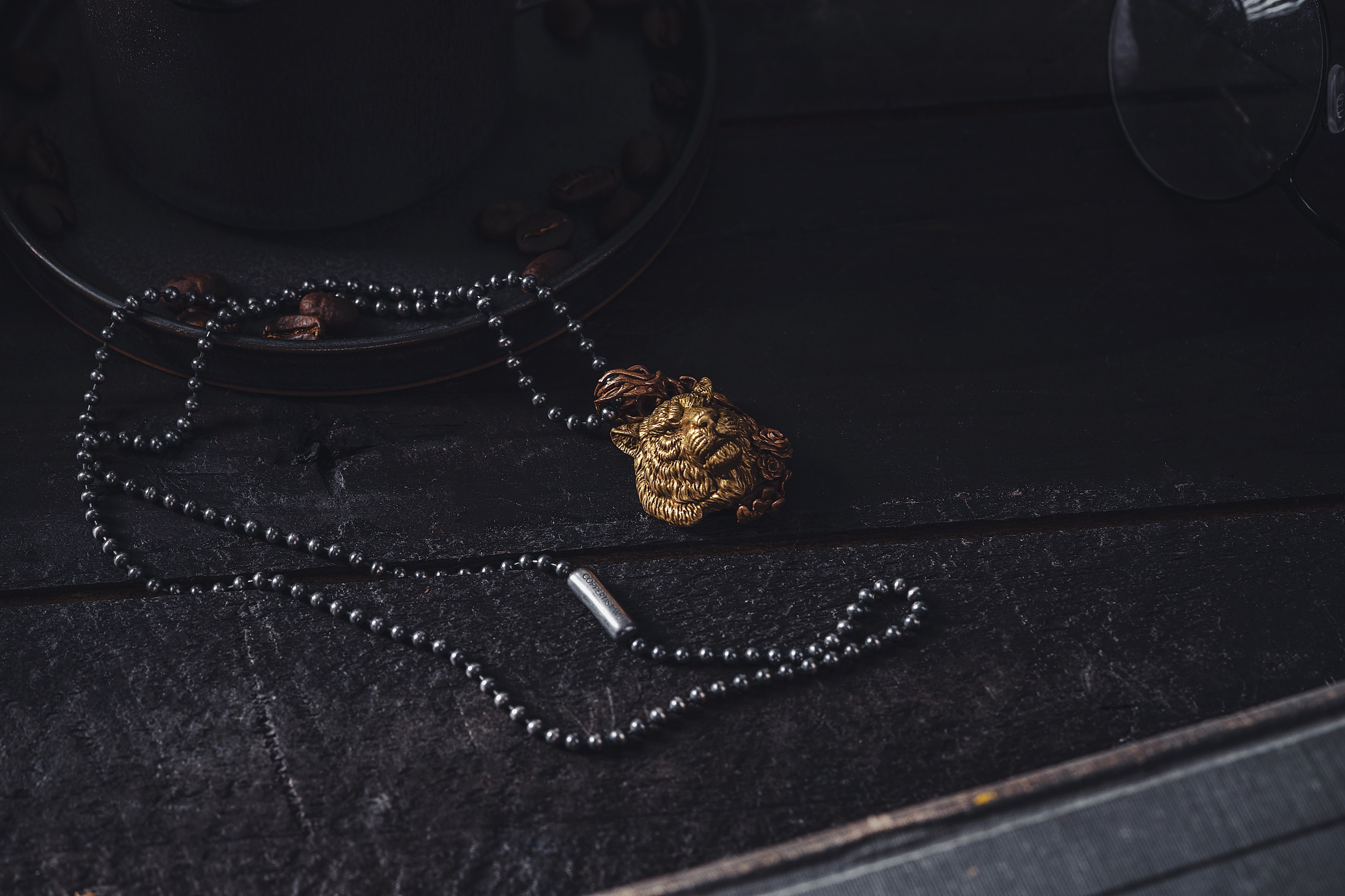 Gold lion-motif pendant necklace photographed in warm sunlight, close up on a neutral background