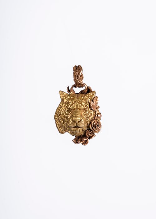 Free Close-up of a gold tiger pendant adorned with intricate floral motifs on a white background. Stock Photo