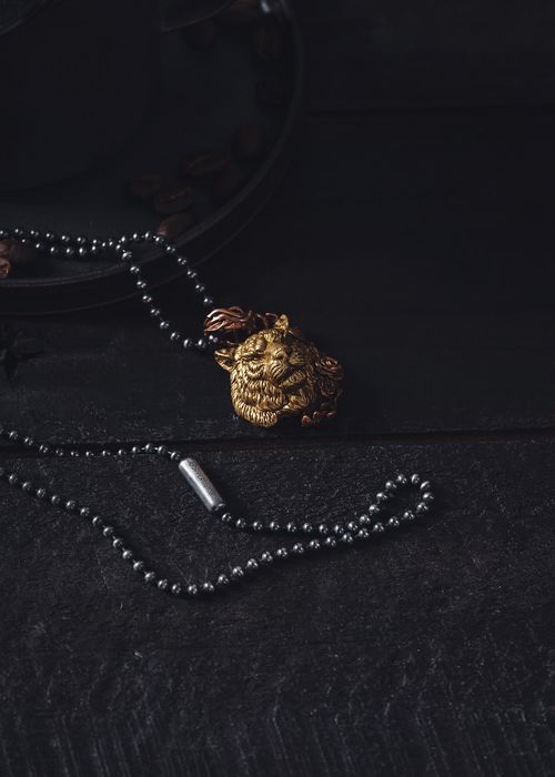 Free Close-up of a tiger pendant necklace on a dark textured background, showcasing intricate jewelry design. Stock Photo