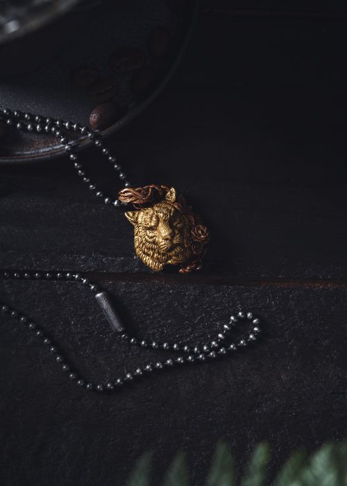Free Close-up of a handmade golden lion necklace on a dark surface. Stock Photo