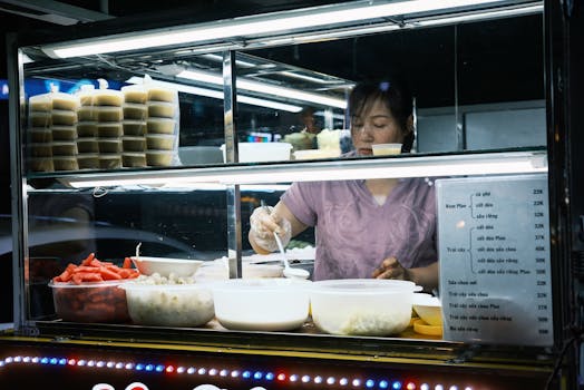 A street vendor prepares traditional Vietnamese desserts at an outdoor food stall at night.