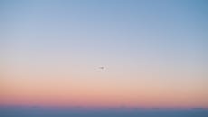 一架孤独的飞机轮廓在柔和的日落天空中飞翔