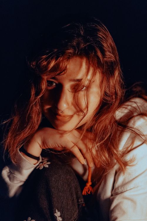 Free A close-up portrait of a smiling woman with long brunette hair, captured in warm lighting. Stock Photo