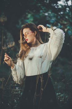 一位穿着白色毛衣的时尚女士在户外摆姿势，四周环绕着大自然的美丽