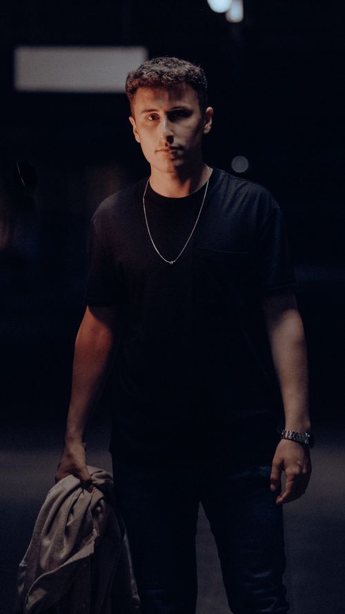 Free Portrait of a fashionable young man in a black t-shirt and neck chain, captured at night. Stock Photo