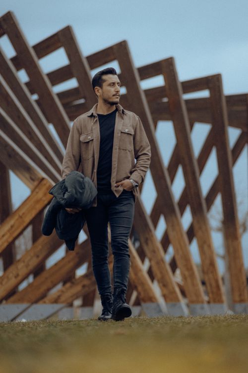 Free Man poses in casual fashion in front of modern architecture, holding a jacket. Stock Photo