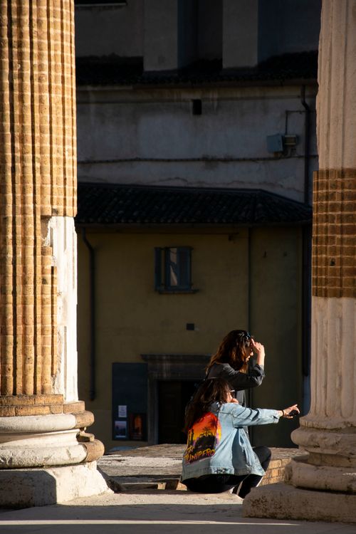 Free Two women discovering ancient columns in Brescia, Italy on a sunny day. Stock Photo
