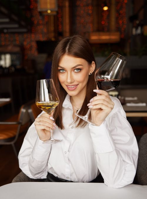 Free A young woman tasting red and white wine in a cozy restaurant setting. Stock Photo