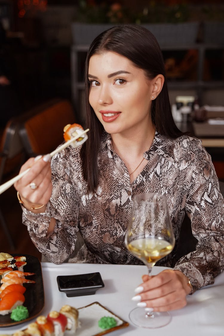 Beautiful Woman In A Restaurant Eating Sushi And Drinking White Wine 