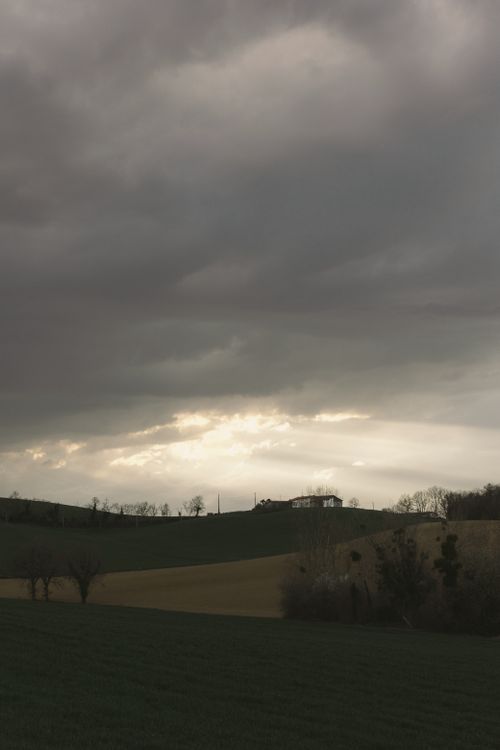 Free Peaceful rural scene with clouds and a hilltop village, perfect for tranquil settings. Stock Photo