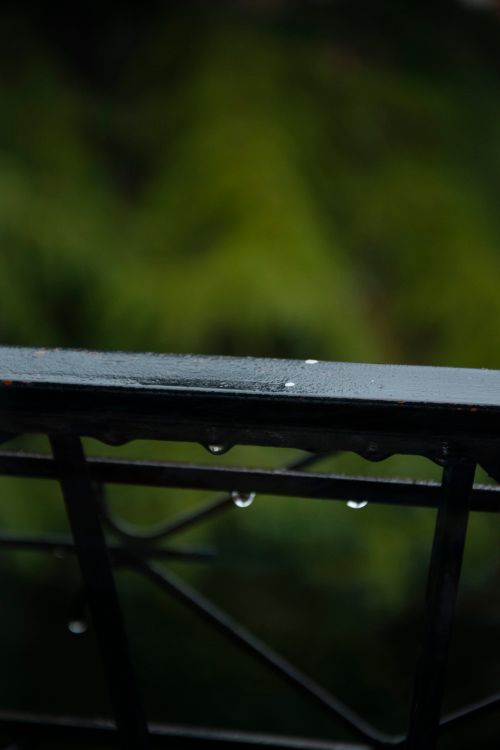 Free Close-up of raindrops on a metal railing in Brescia, Italy, with blurred green background. Stock Photo