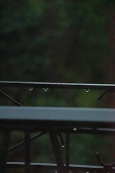 Raindrops glistening on a metal railing in Brescia, creating a tranquil mood.